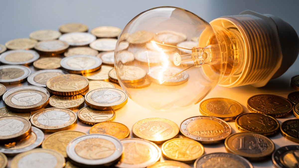 De l'argent éparpillé autour d'une ampoule, le coût de l'énergie